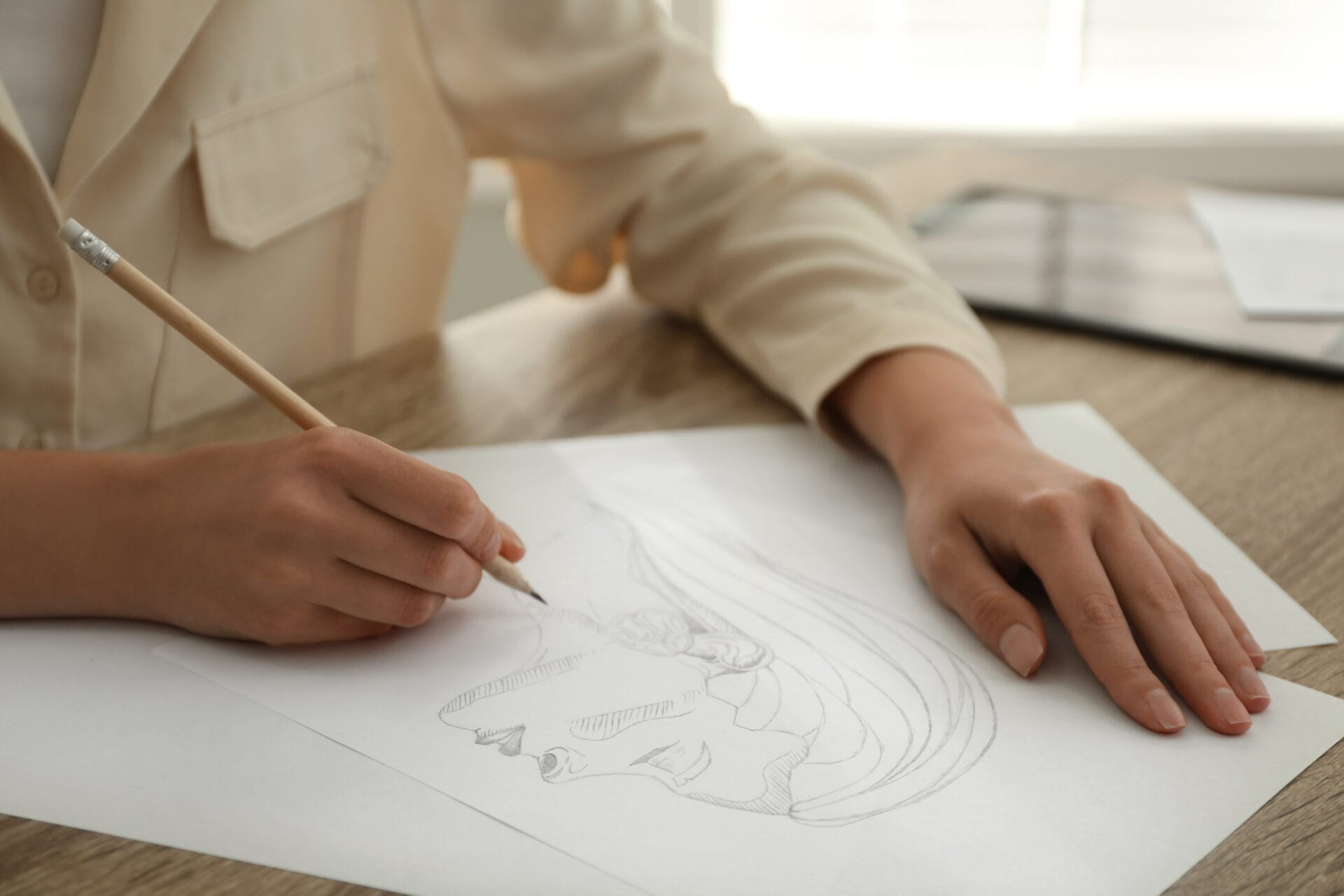 Woman drawing girl's portrait with pencil on sheet of paper at wooden table, closeup on Drawing Ideas for Artists