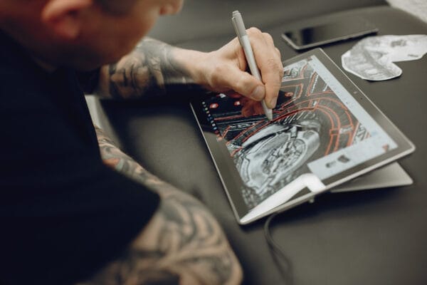 Tatooed man drawing on a digital tablet illustrating Drawing Ideas for Artists